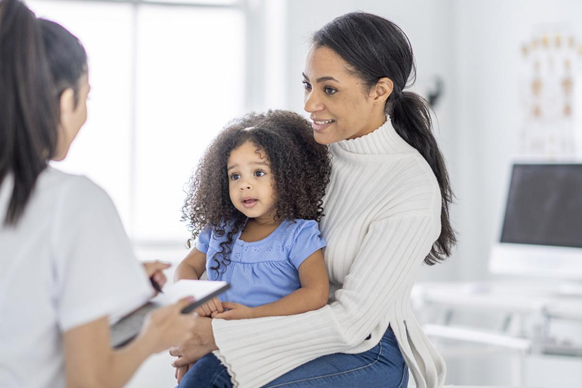 Mother sits in the doctor's office with toddler on lap 