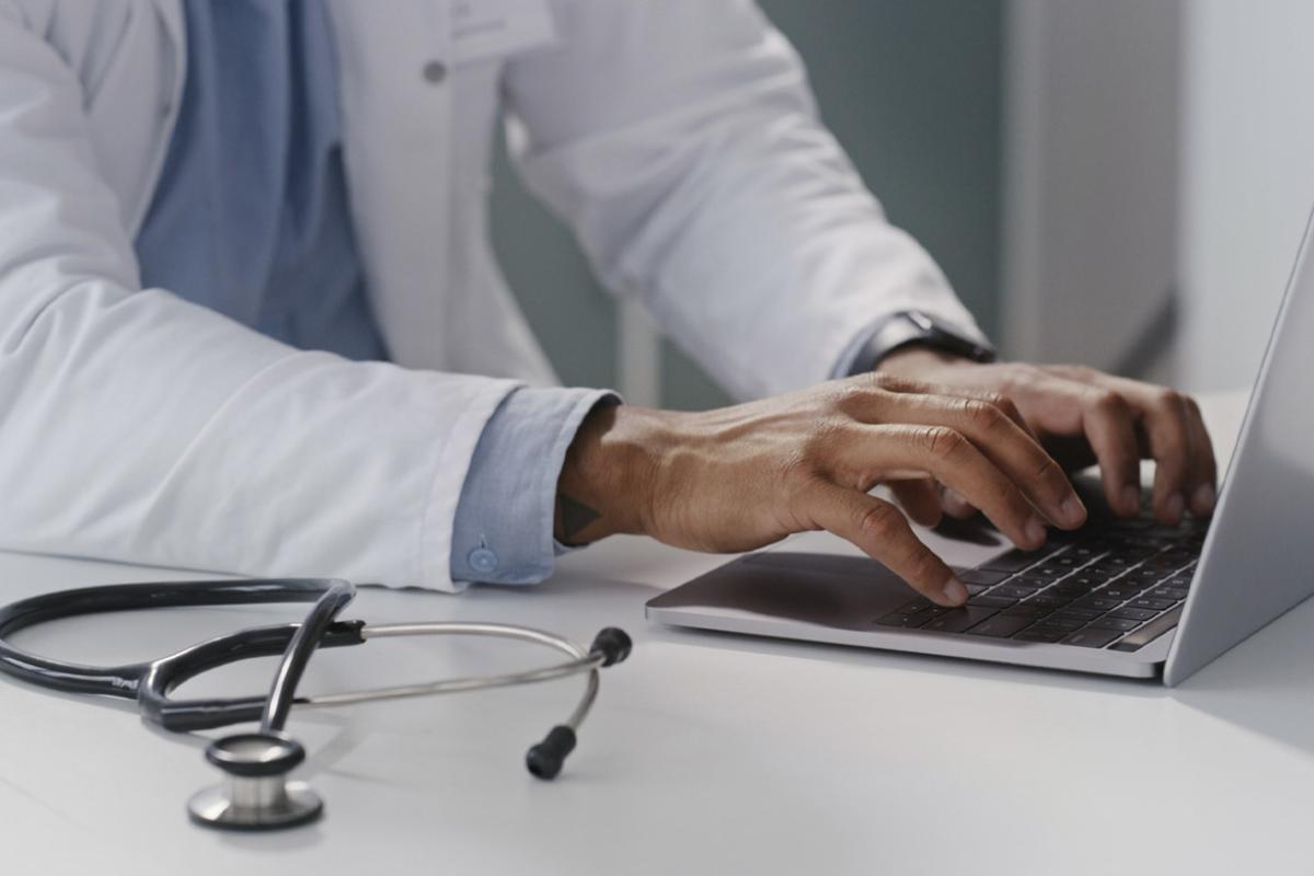 Physician types on a laptop