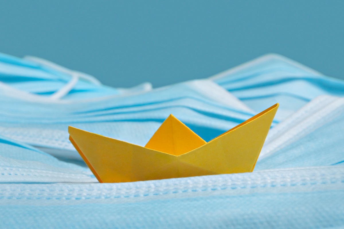 Yellow paper boat on top of medical face masks
