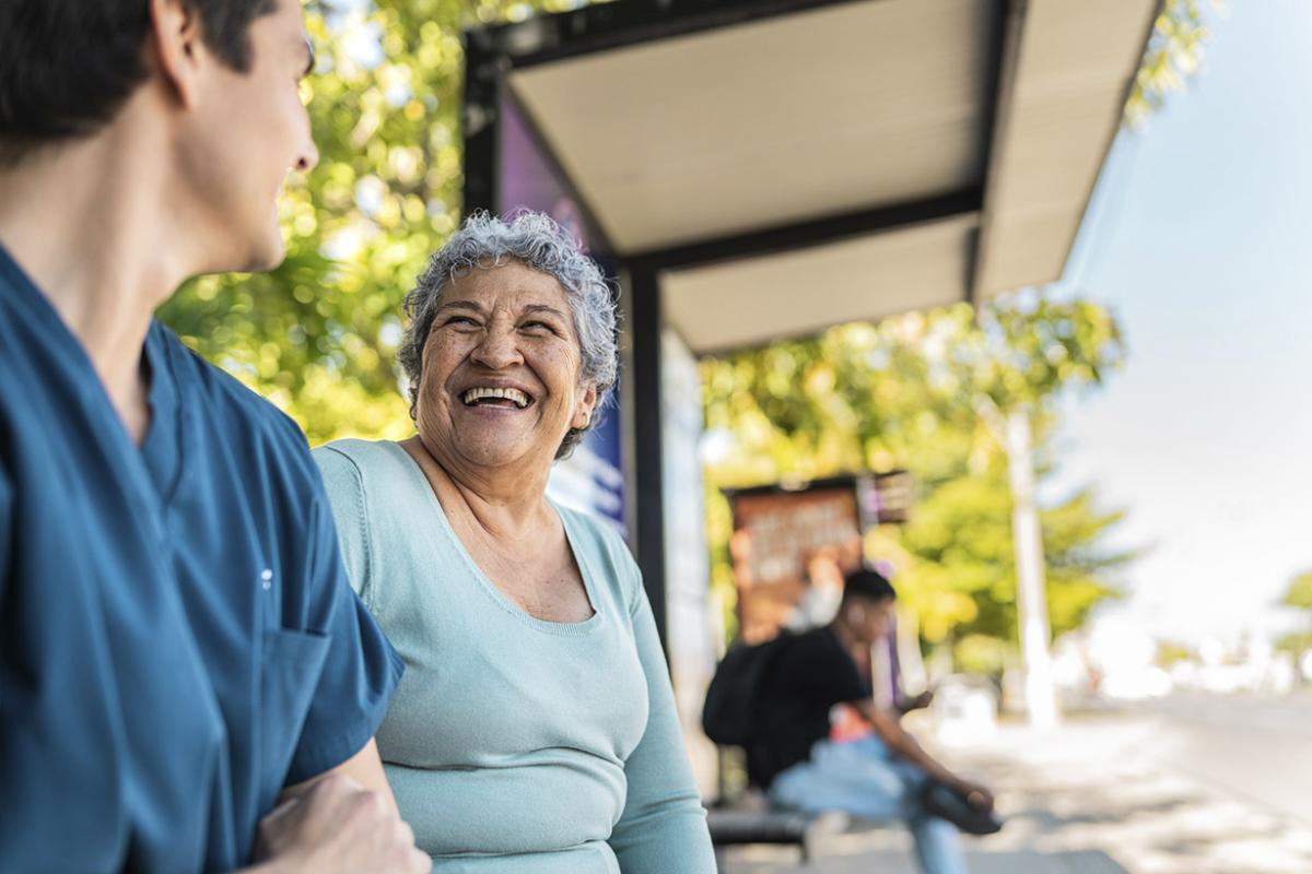 Two smiling people at a bus stop