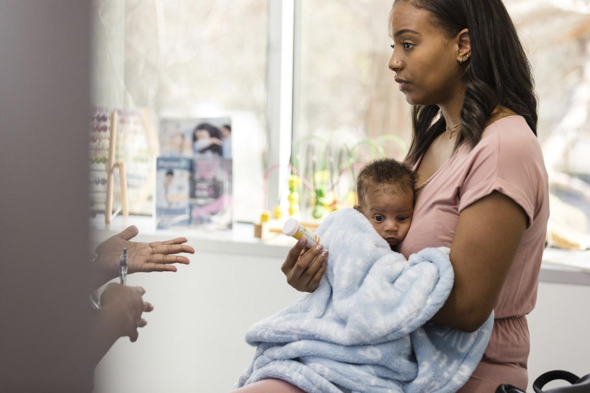 Mom holding baby gets medicine from doctor