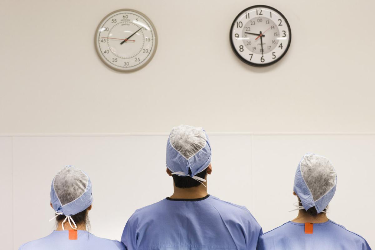 Three physicians facing toward two clocks on a wall