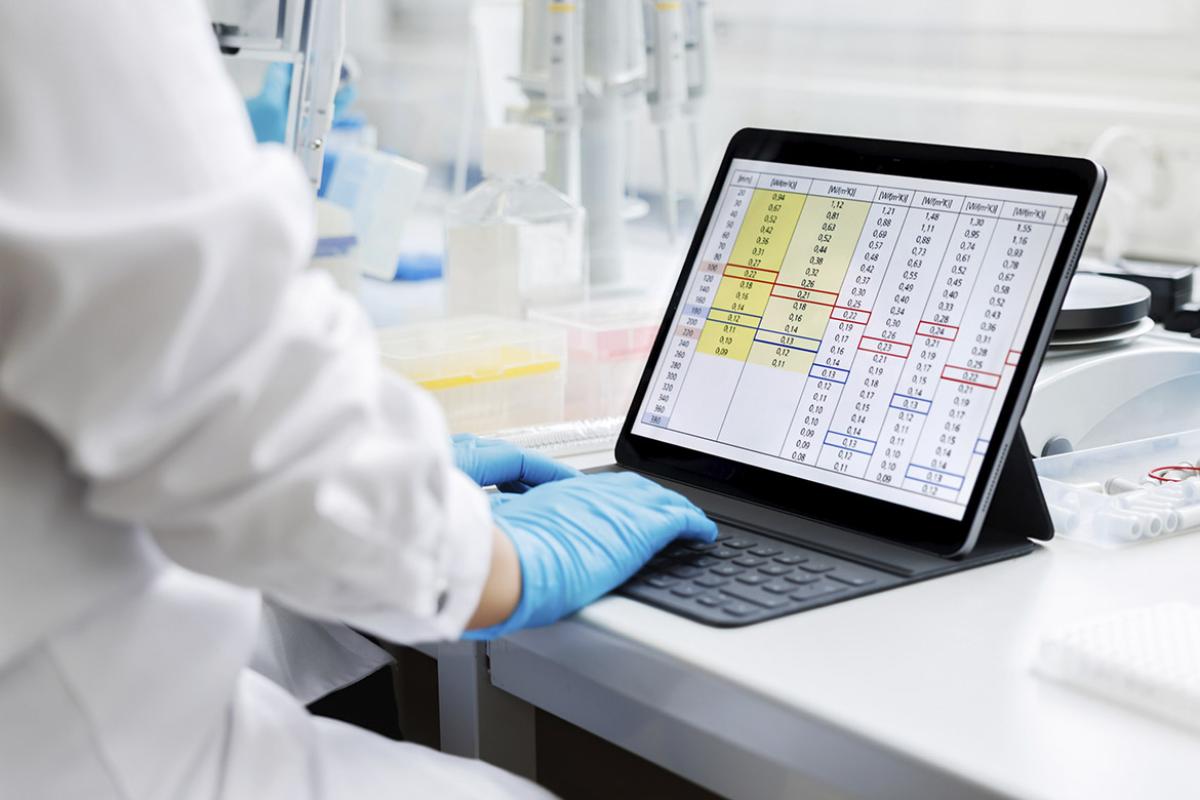 Researcher works with a digital tablet displaying detailed data tables