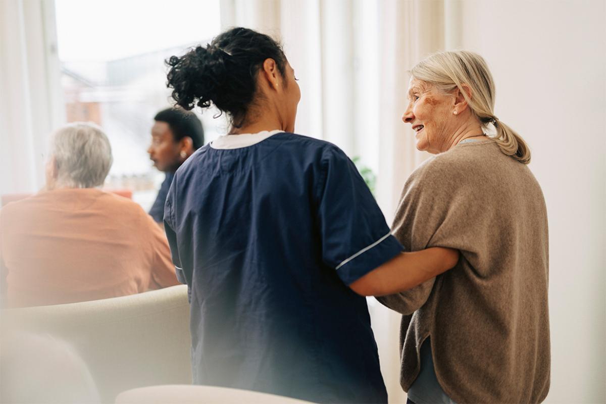 Health care worker walking arm in arm with elderly patient