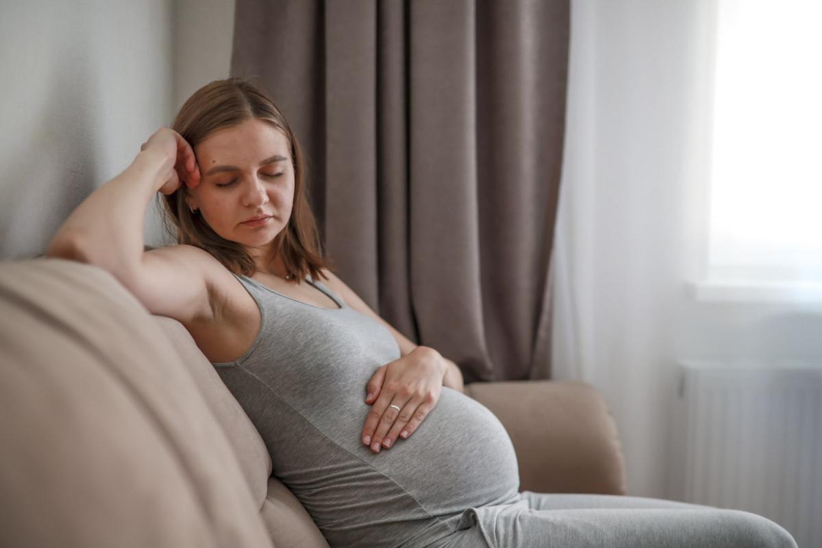 A pregnant woman sits on a sofa