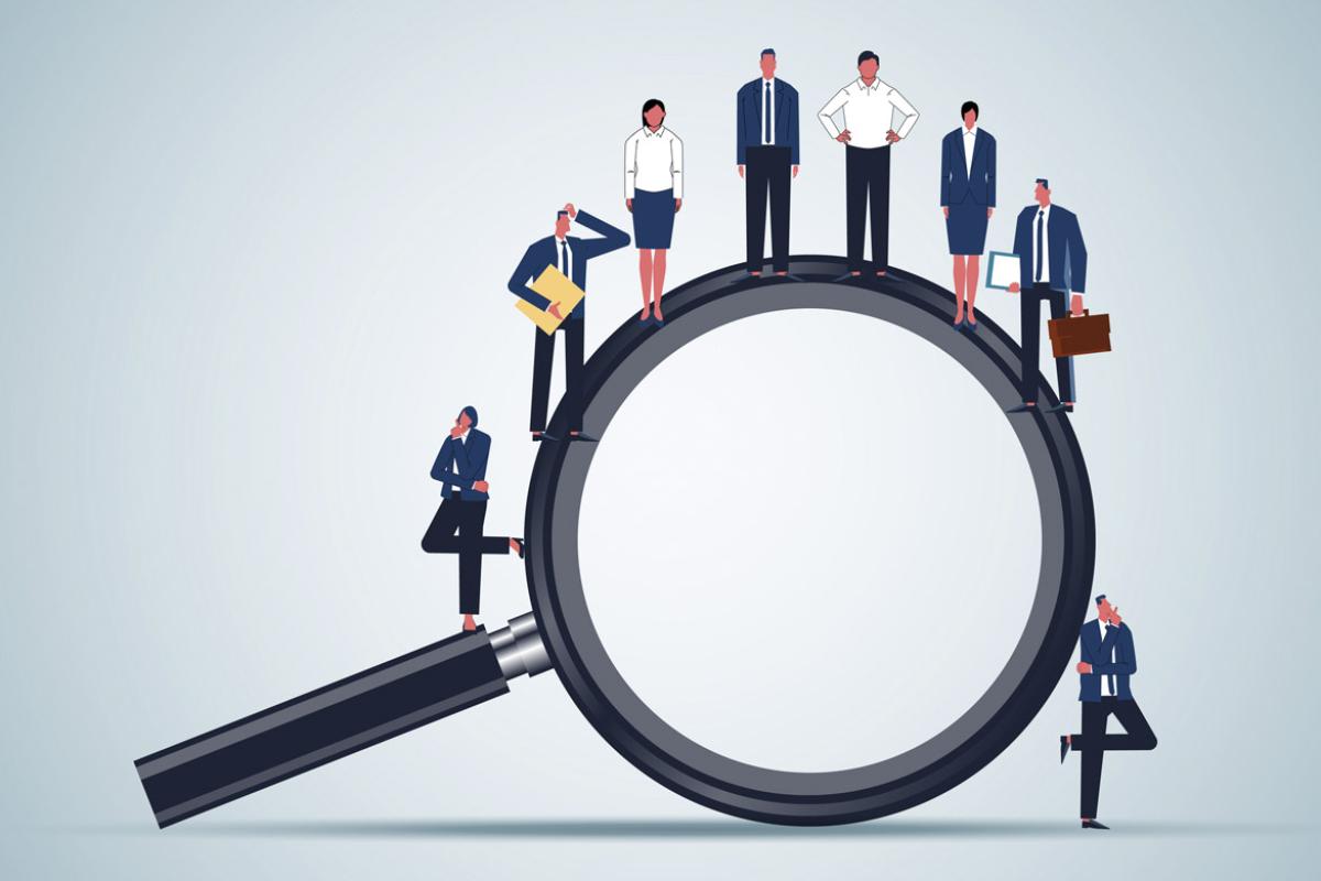 Figures stand on a giant magnifying glass