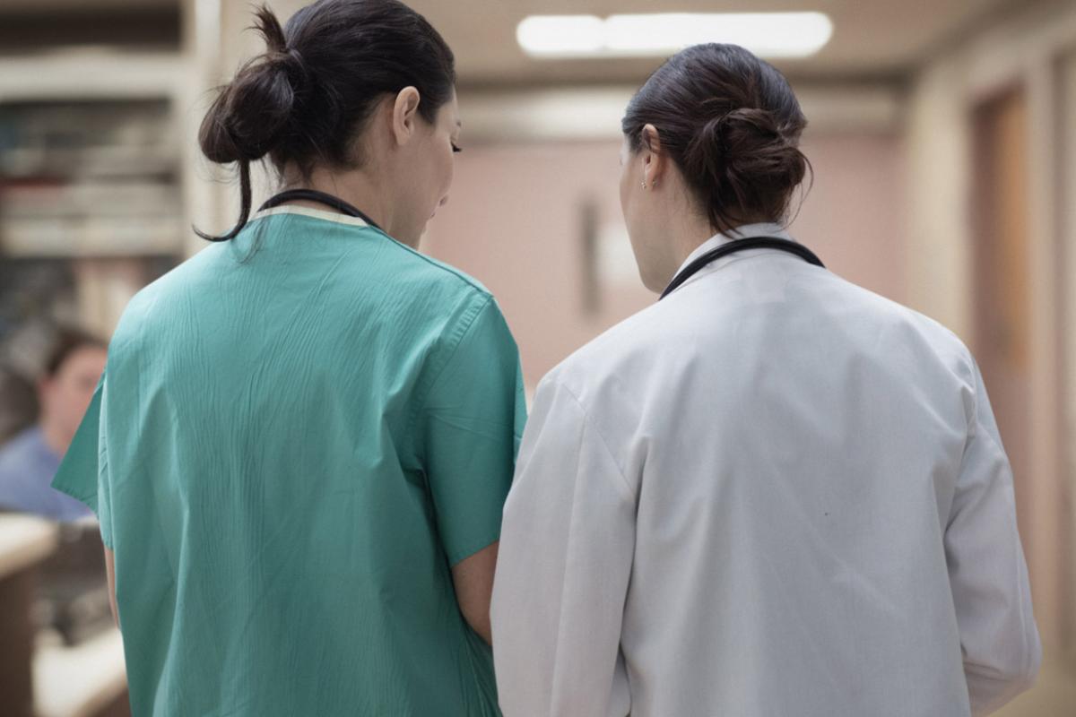 Two healthcare workers talking in hospital hallway