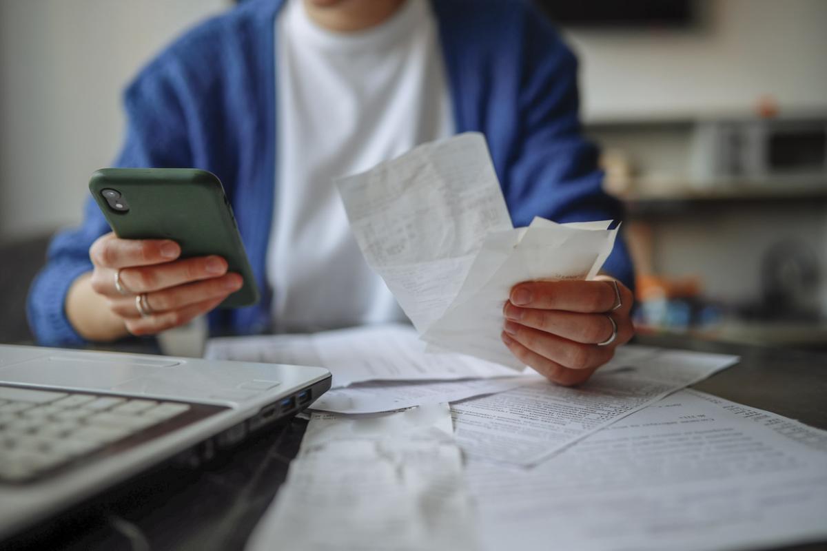 Person holds receipts in one hand and smartphone in another hand