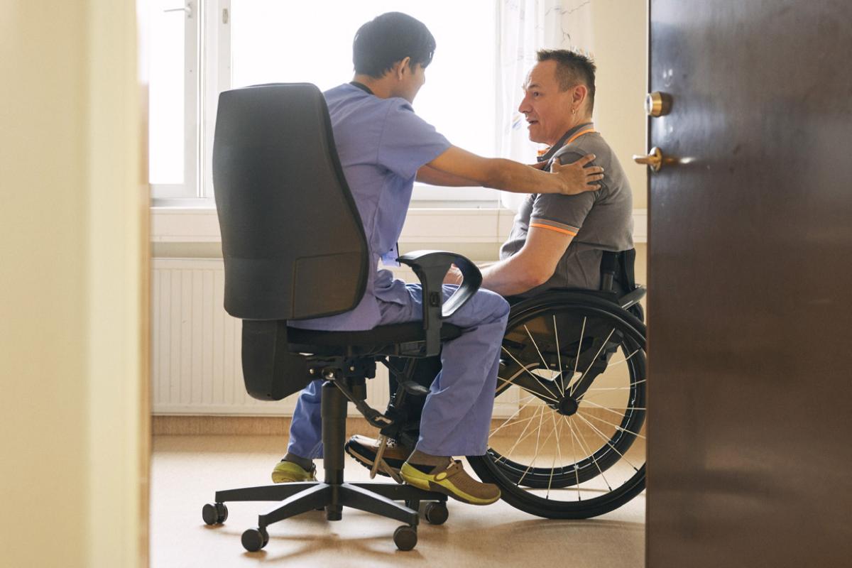 Doctor places hand on patient in a wheelchair