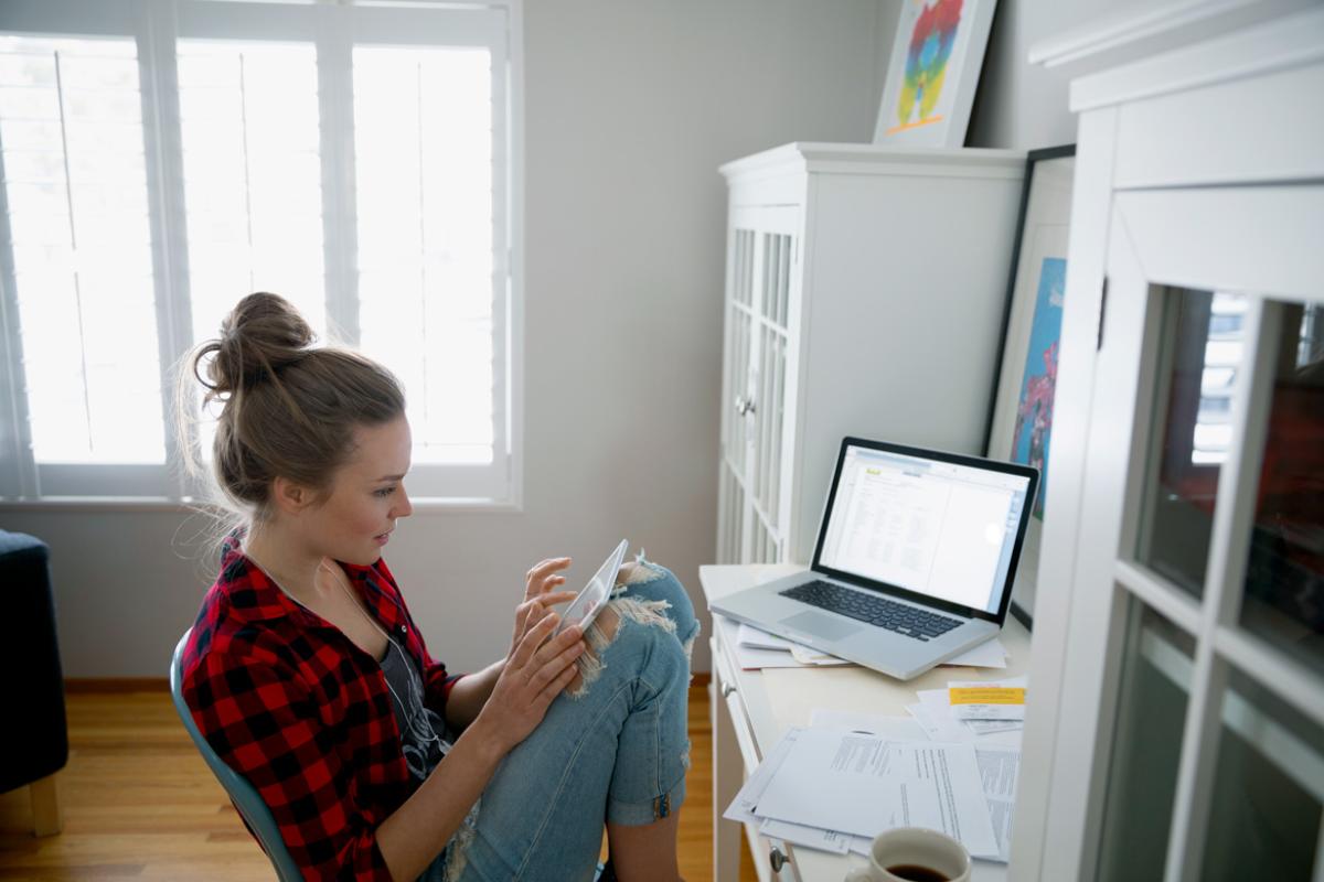 A medical student sits in her apartment and explores financial aid options on her tablet.