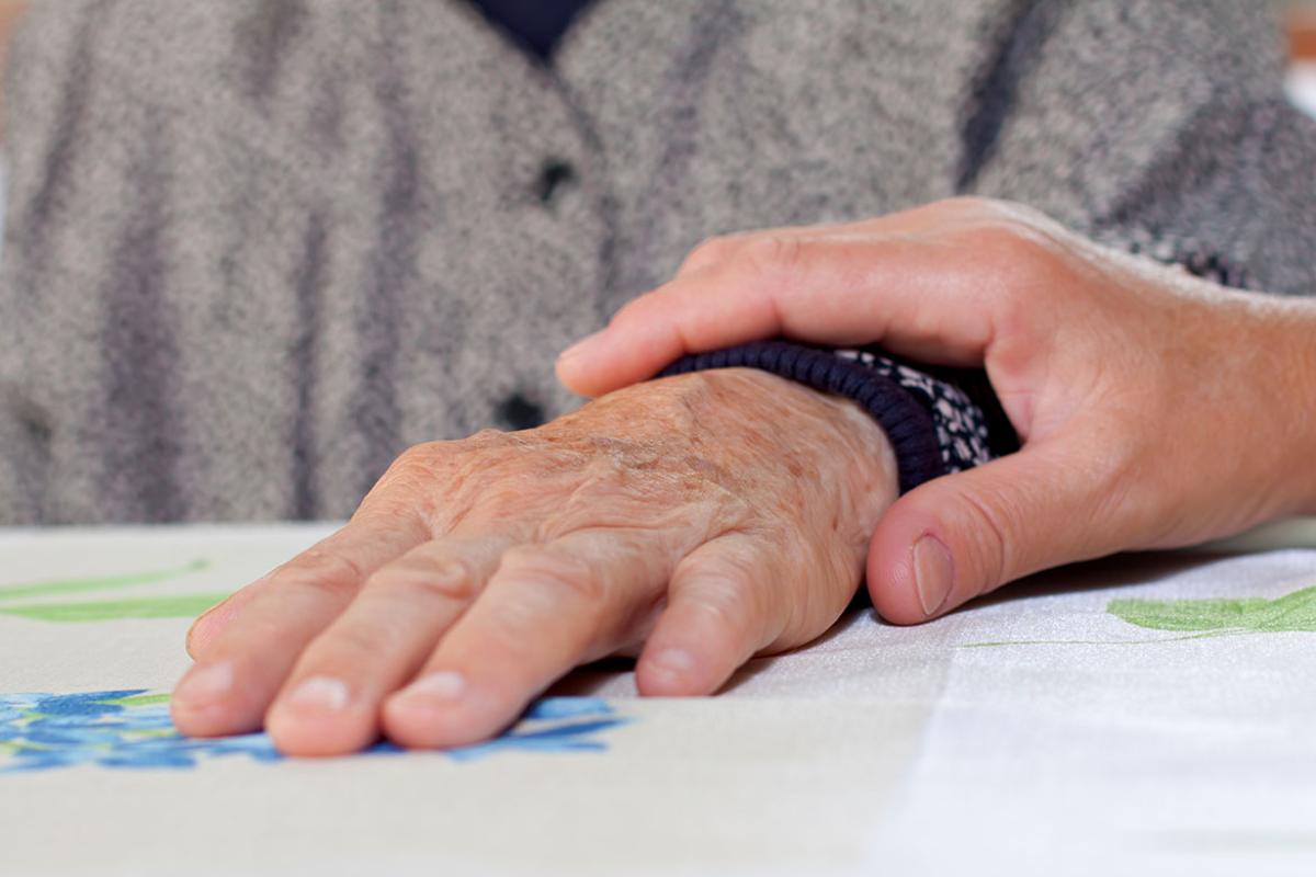 One hand holding the wrist of an older patient