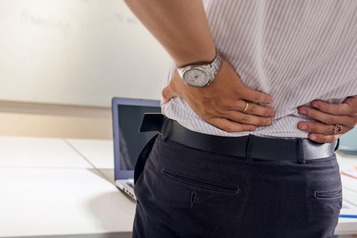 Man standing rubbing his sore back.
