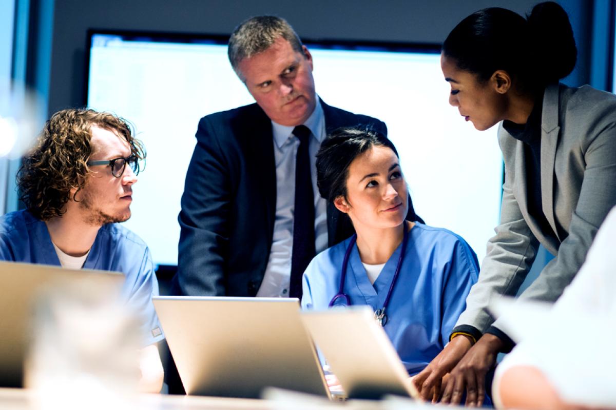 Four people gather around a computer for teamwork.