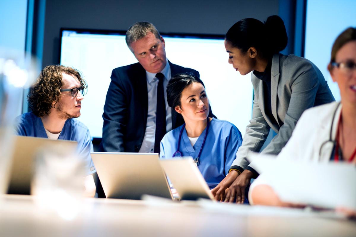 Four people gather around a computer for teamwork.