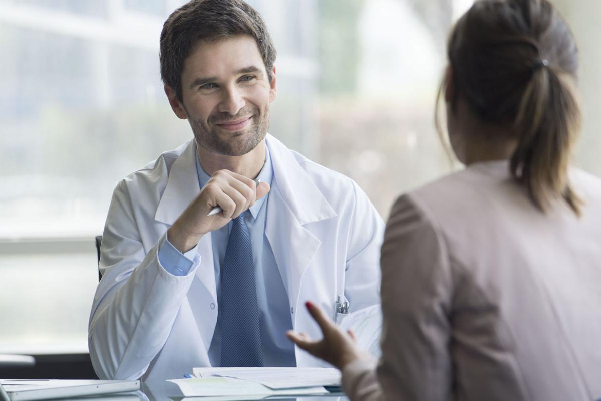 Smiling physician listens to a patient.