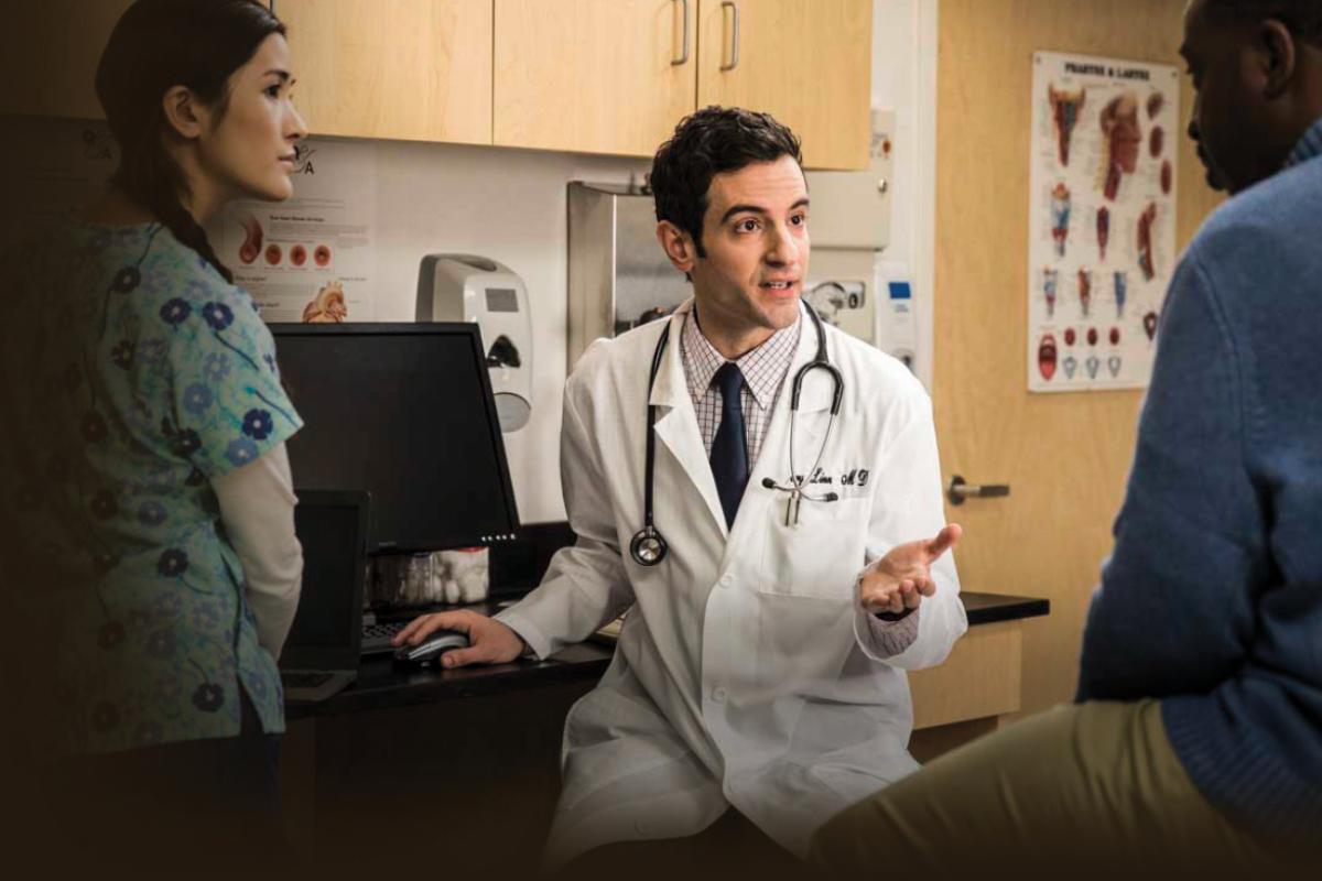 Physician and assistant conversing with a patient.