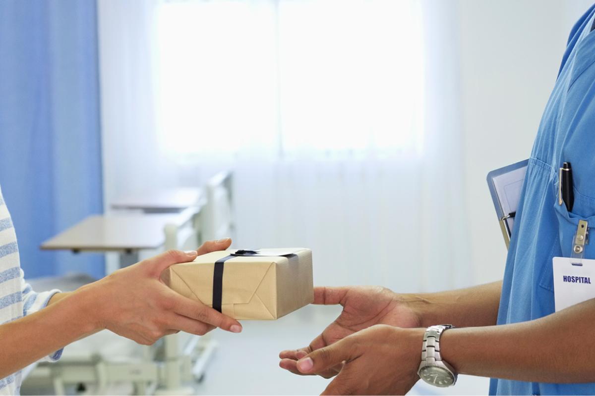 Patient handing a physician a small gift. 