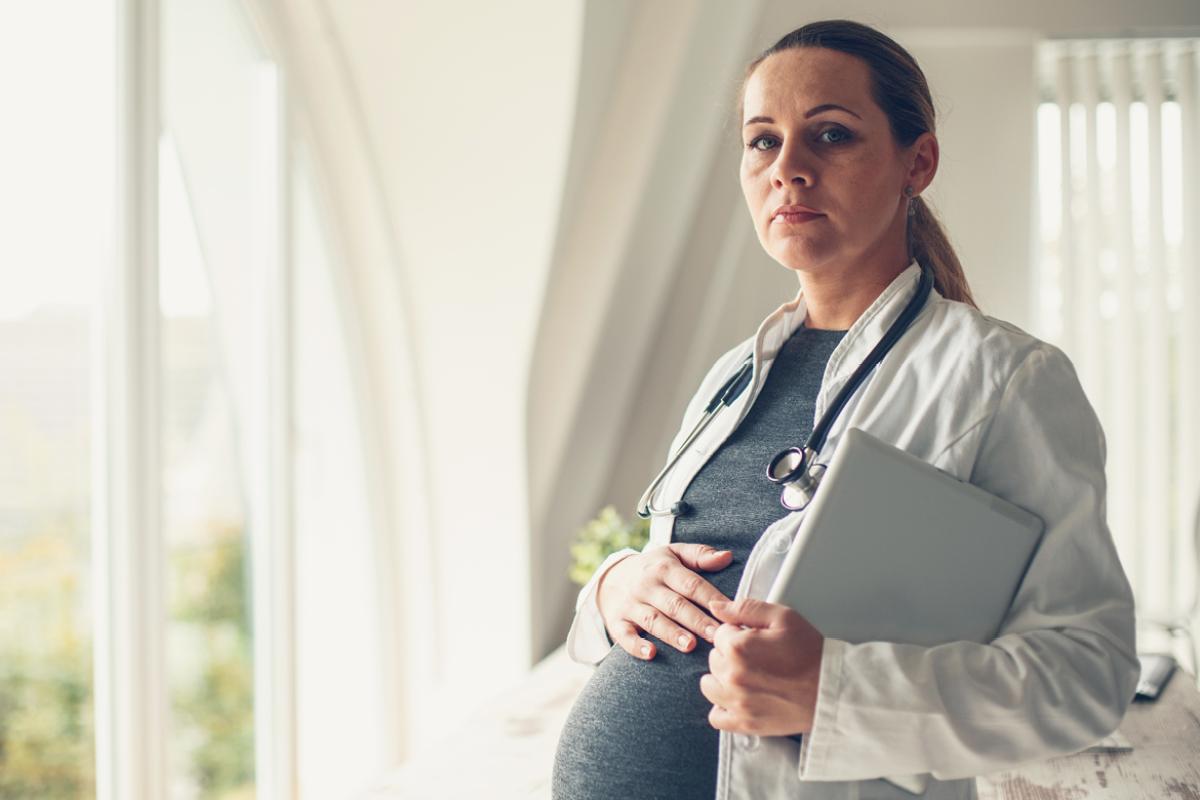 Pregnant physician with her hand resting on her belly. 
