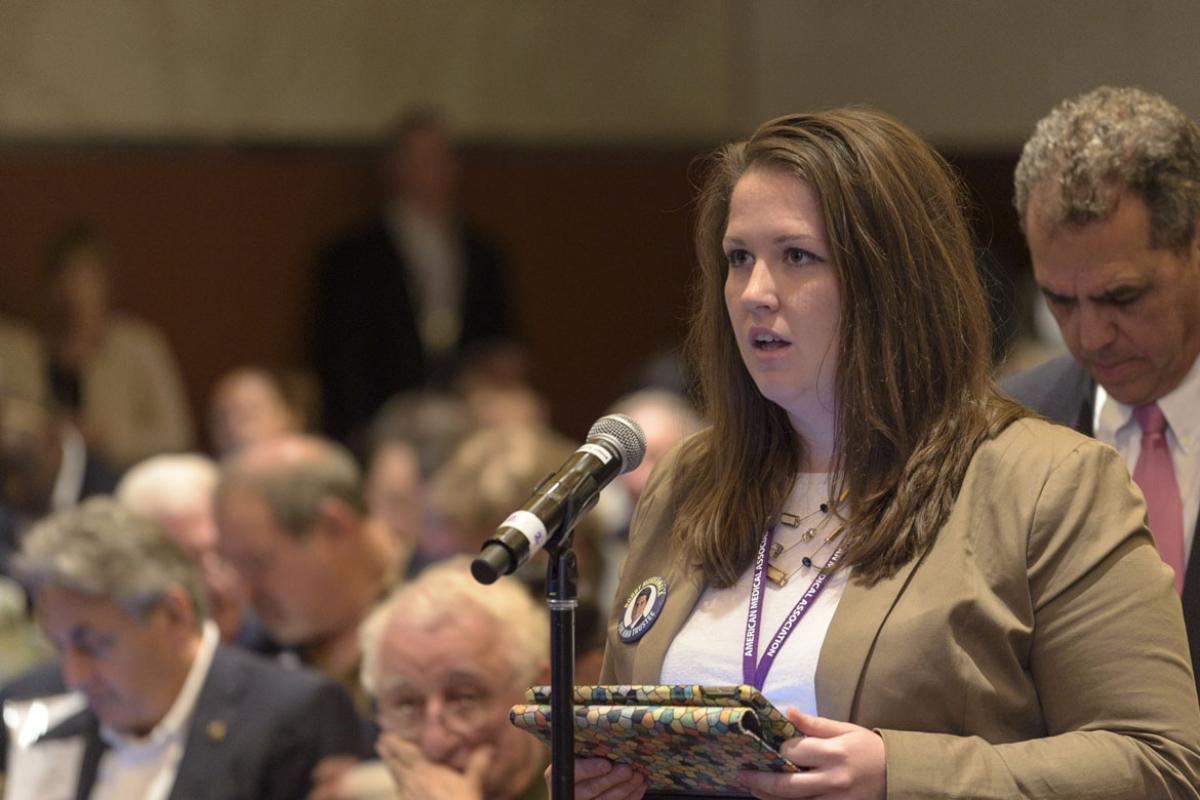 Physician standing at a microphone making a comment. 