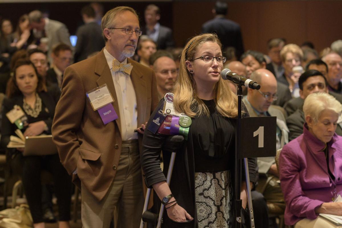 Two physicians stand waiting their turn to be heard. 