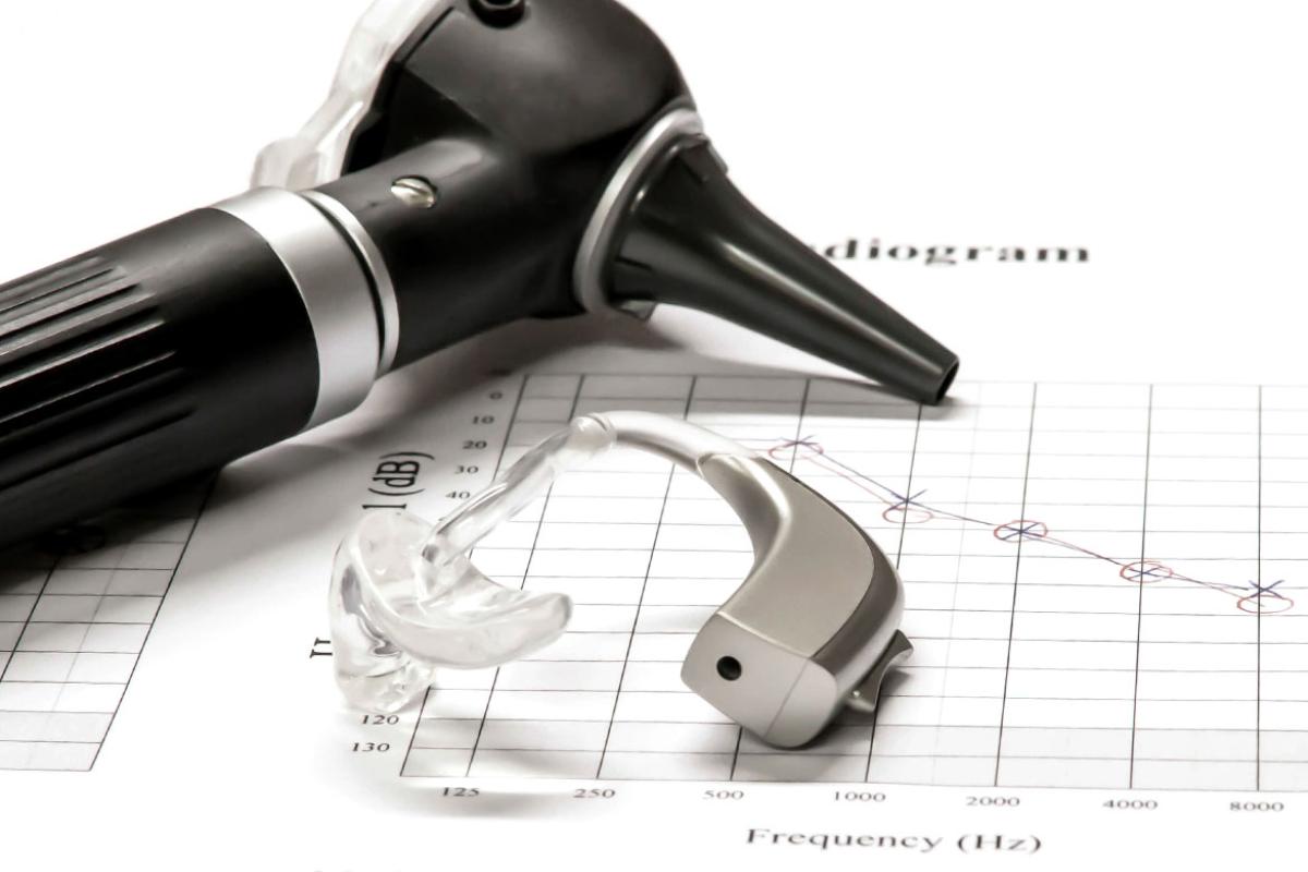 Ear scope and hearing aid resting on medical chart. 