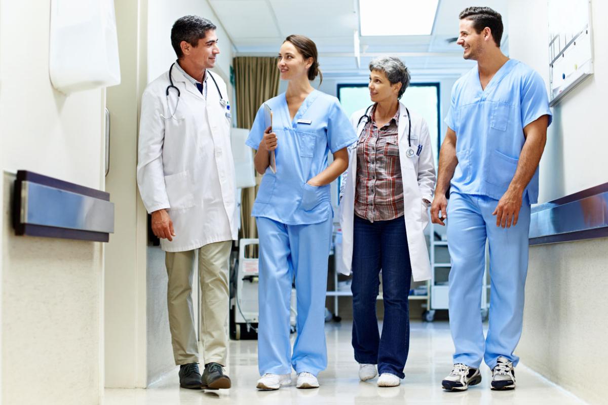 Physicians walk down hallway of hospital. 
