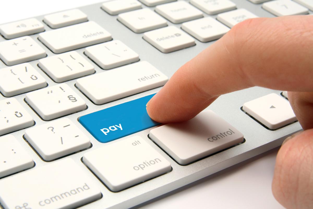 Close-up of a keyboard with a finger pressing a 'pay' key.