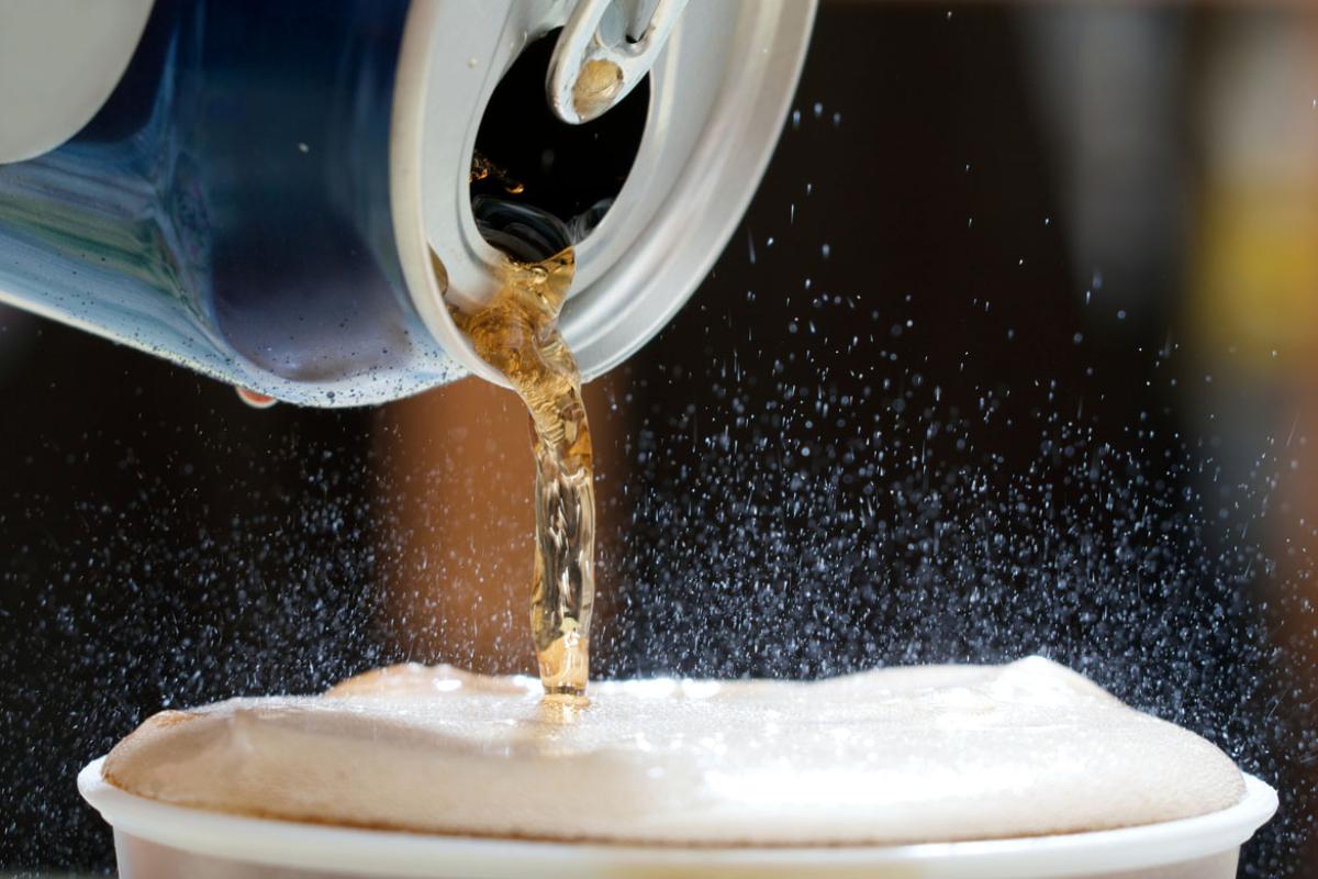 Sugary soda being poured from can into a glass. 