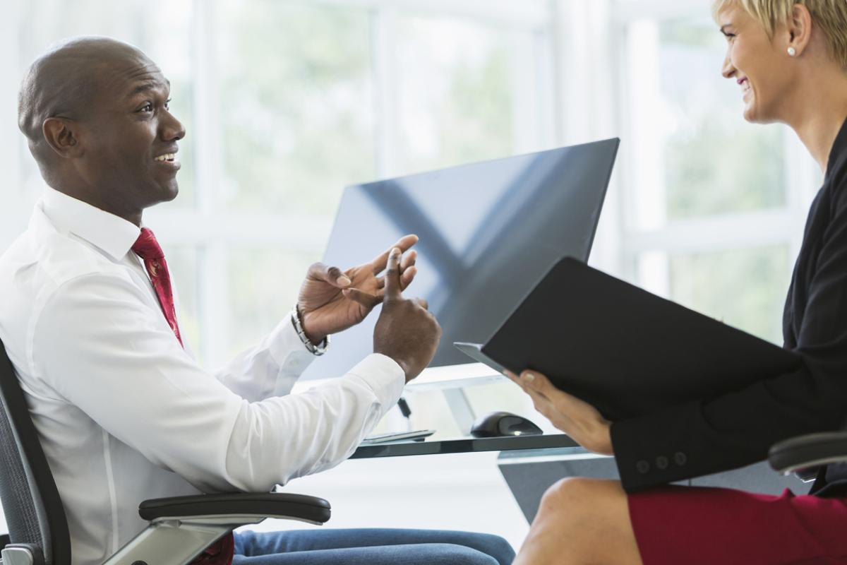 Man and woman talking to each other by computer desk