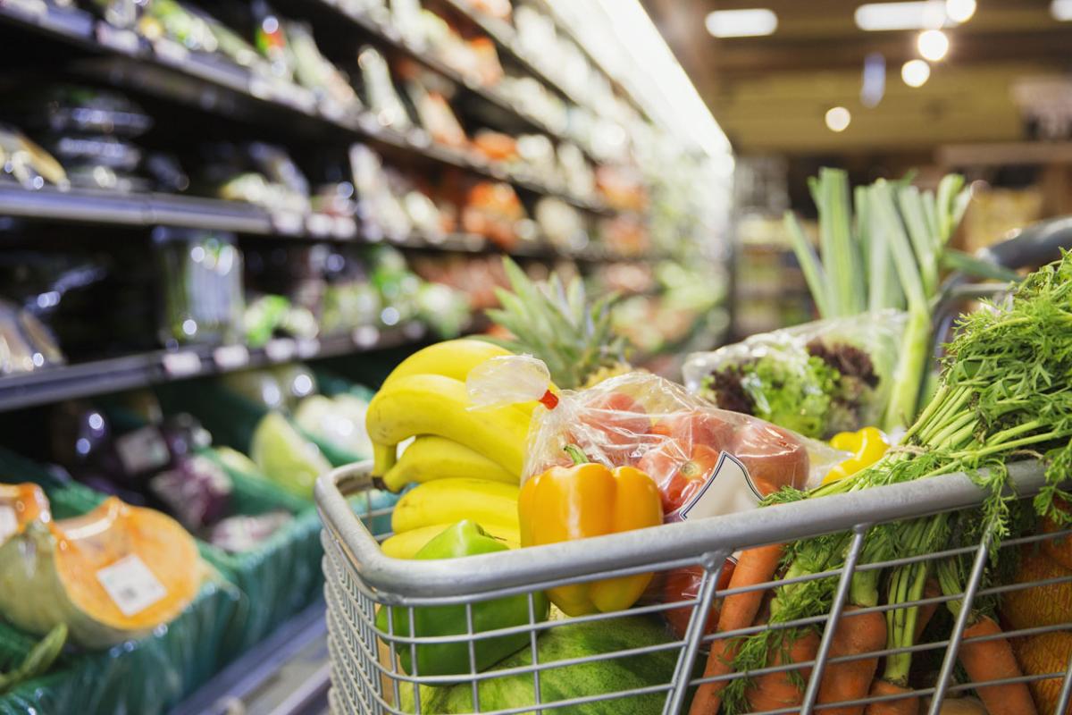 Bananas, peppers, apples, carrots, and lettuce in a shopping cart