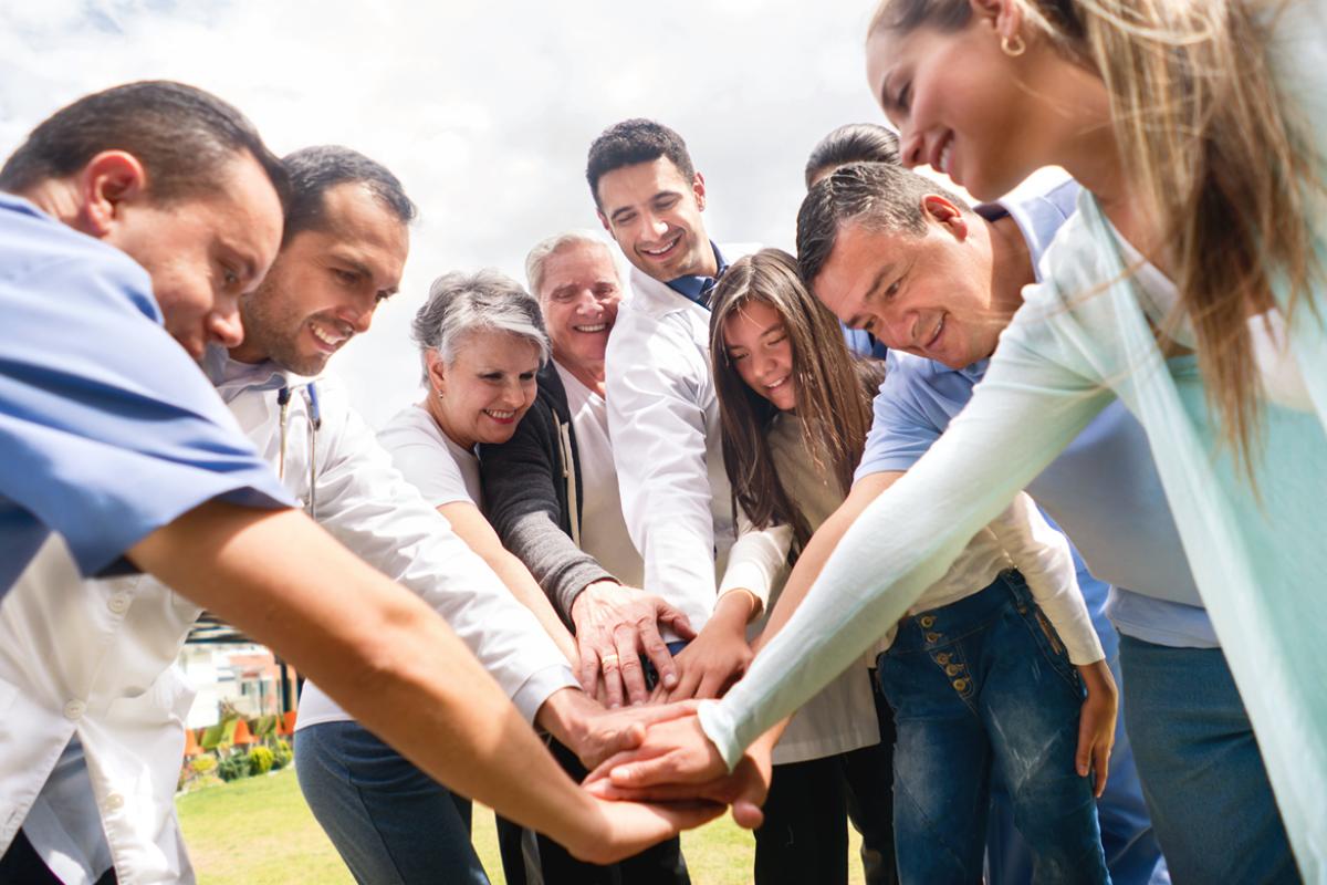 Medical professionals putting their hands together in the middle of a group circle