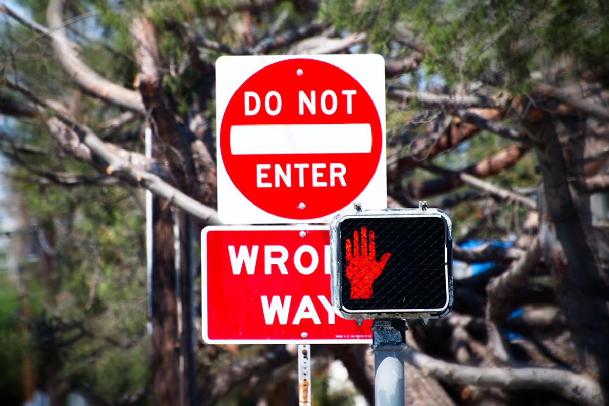 Two traffic signs "Do Not Enter" and "Wrong Way" and red flashing crosswatch sign.