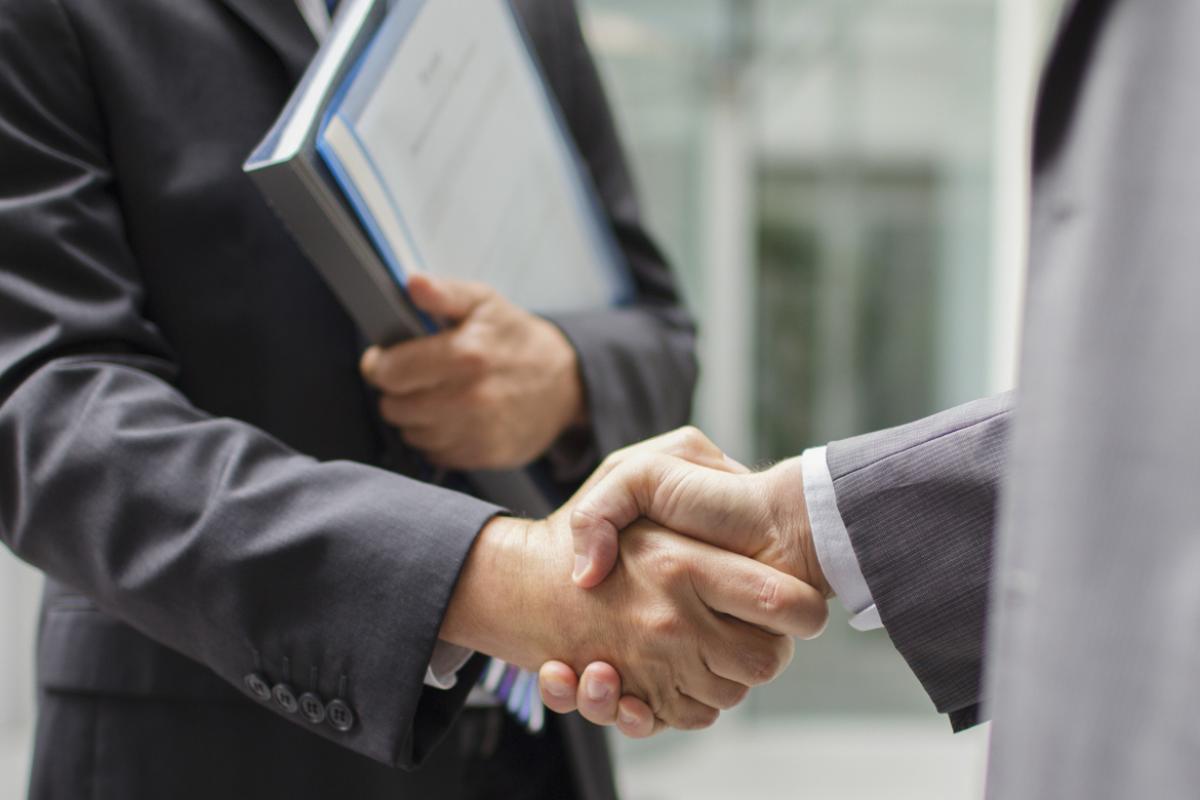 Two businessmen shaking hands outside of a building