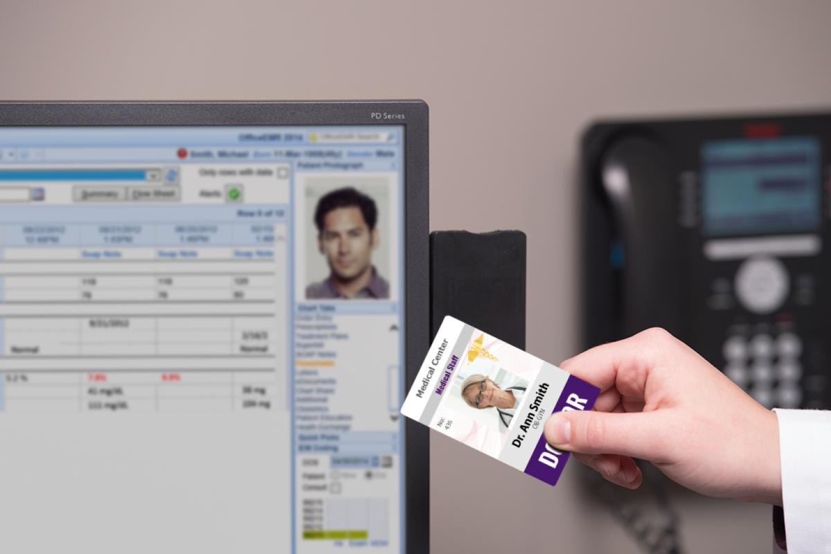 A female doctor prepares to use her swipe card to access her computer terminal.
