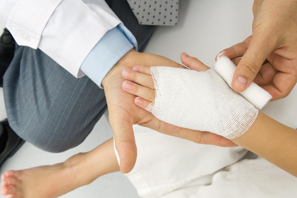 A doctor bandages a patient's hand.