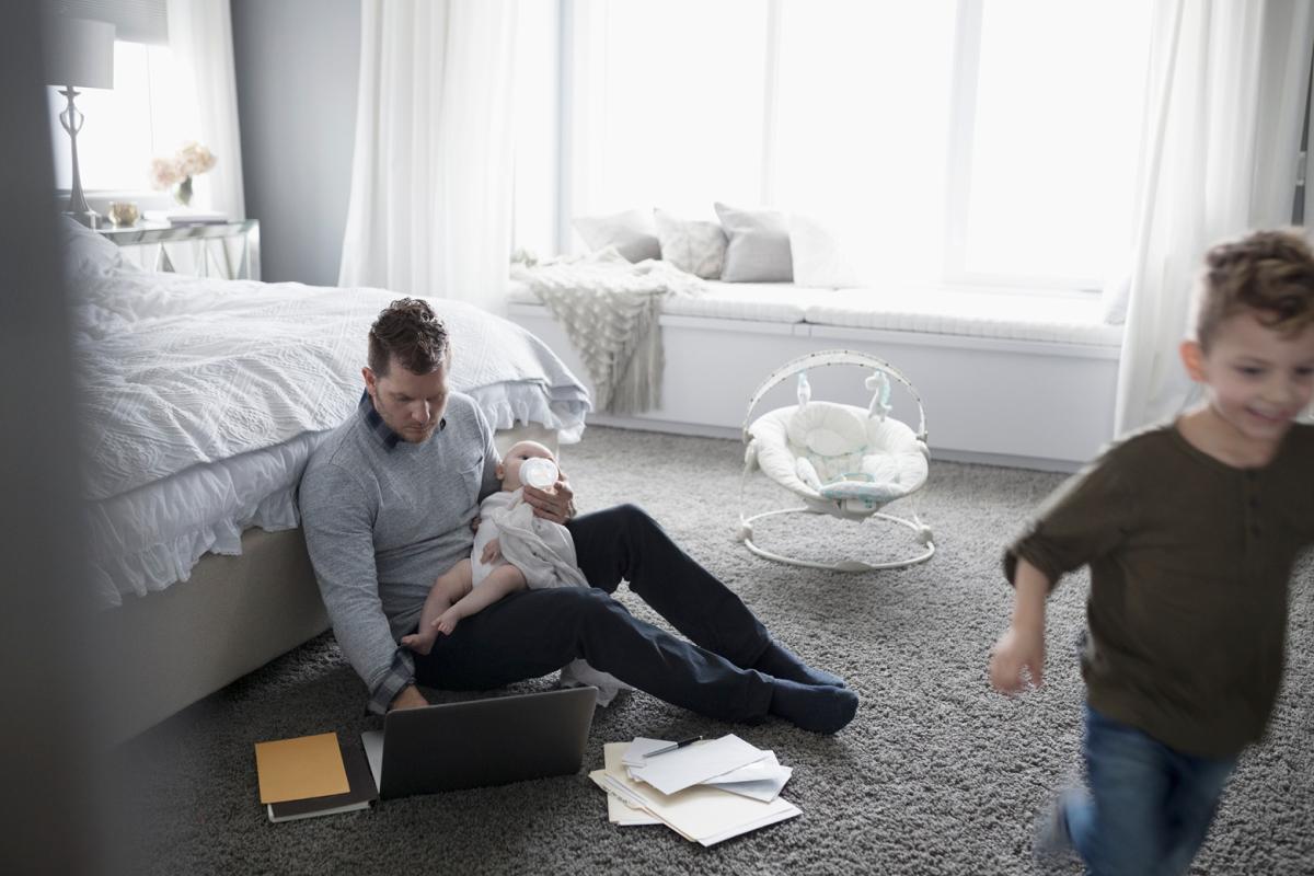 Man with two kids and working on a laptop