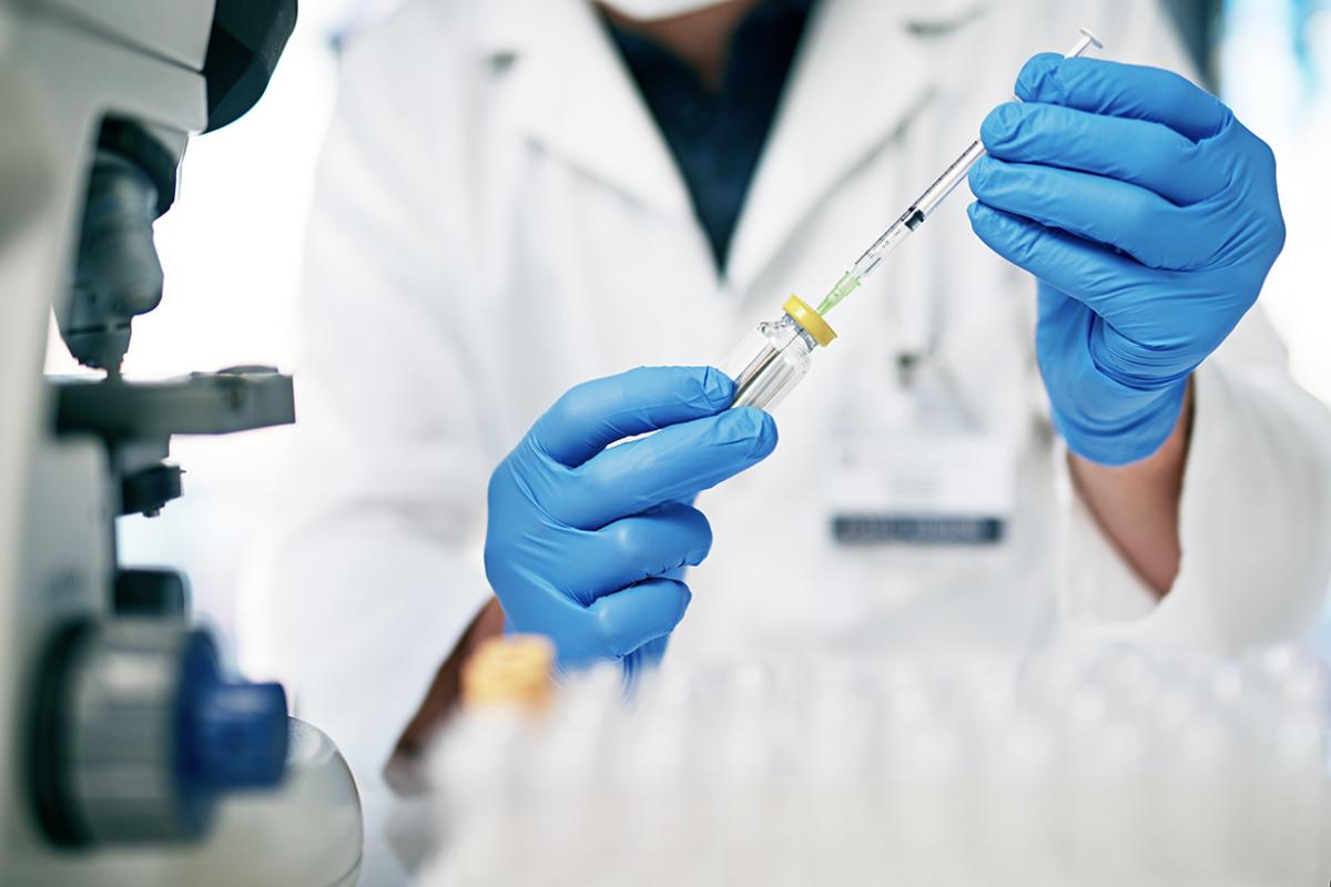 Medical professional inserts needle into bottle