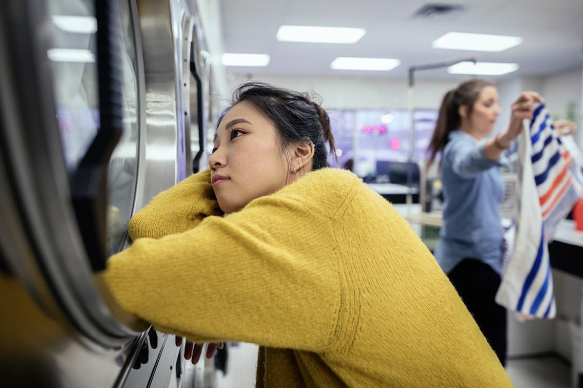 Woman staring into washing machine, daydreaming
