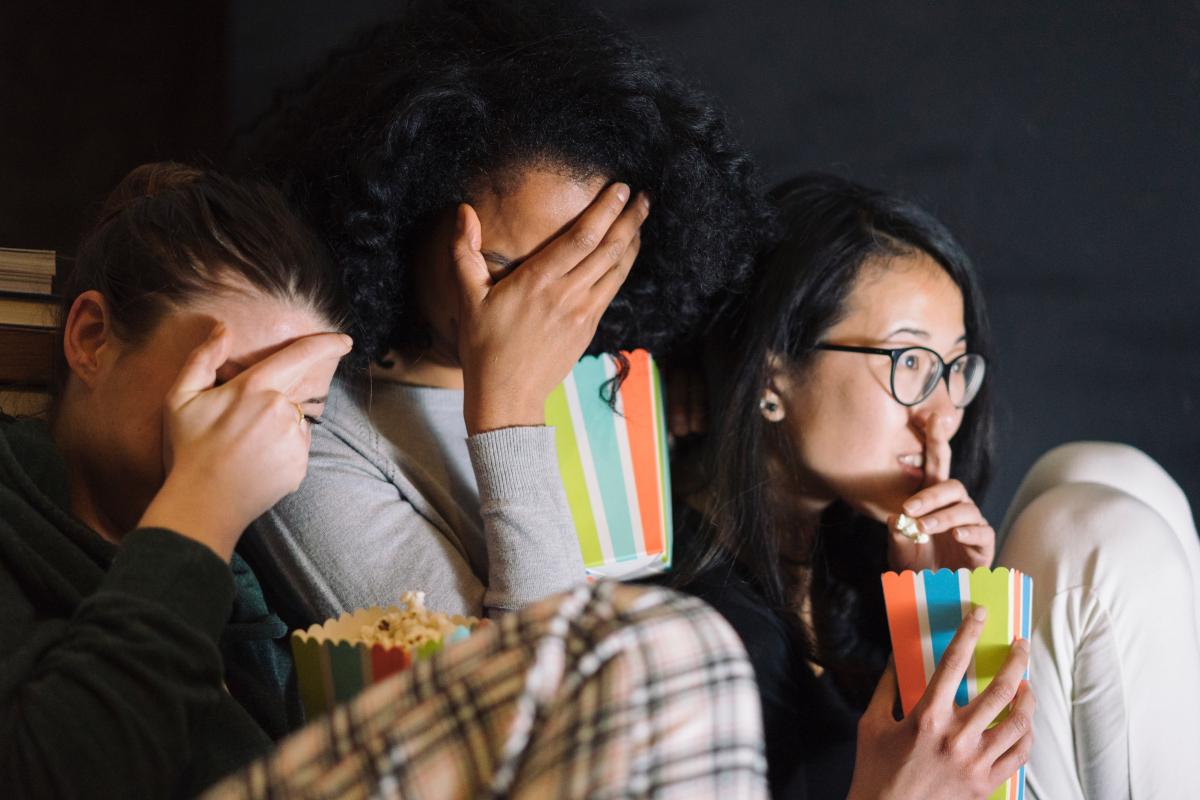 Group of girls watching TV and eating popcorn